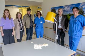 Spender und Spendenempfänger stehen um einen Tisch, auf den ein Hund projiziert wird.