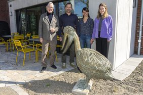 Mehrere Personen stehen hinter einem Pelikan aus Bronze