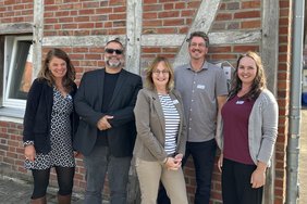 Mitarbeitende der Alexianer IBP Suchtberatungsstelle in Coesfeld stehen mit dem Vortragenden vor einer Wand auf dem Alten Hof Schoppmann.