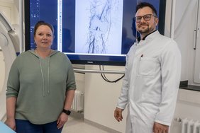 Zwei Personen stehen vor einer Gefäßdarstellung