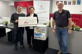 Drei Personen halten einen Scheck