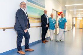 Vier Personen stehen vor einem großen Bild