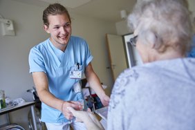 Ein Krankenpfleger bringt einer Patientin Medikamente